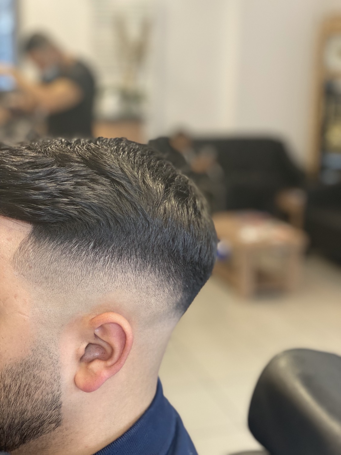 Nahaufnahme eines frisch geschnittenen Fades: oben dunkles Haar, seitlich fein auslaufend bis zur Haut